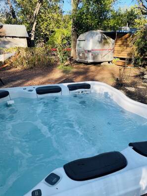 Ein Whirlpool in einem Hinterhof mit einer Holzterrasse und einem Wohnwagen im Hintergrund.