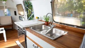 A compact kitchen with a double sink, wooden countertop, and a window providing a view of greenery outside.