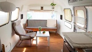 A compact RV interior with a seating area, a table with a plant, and a kitchenette.