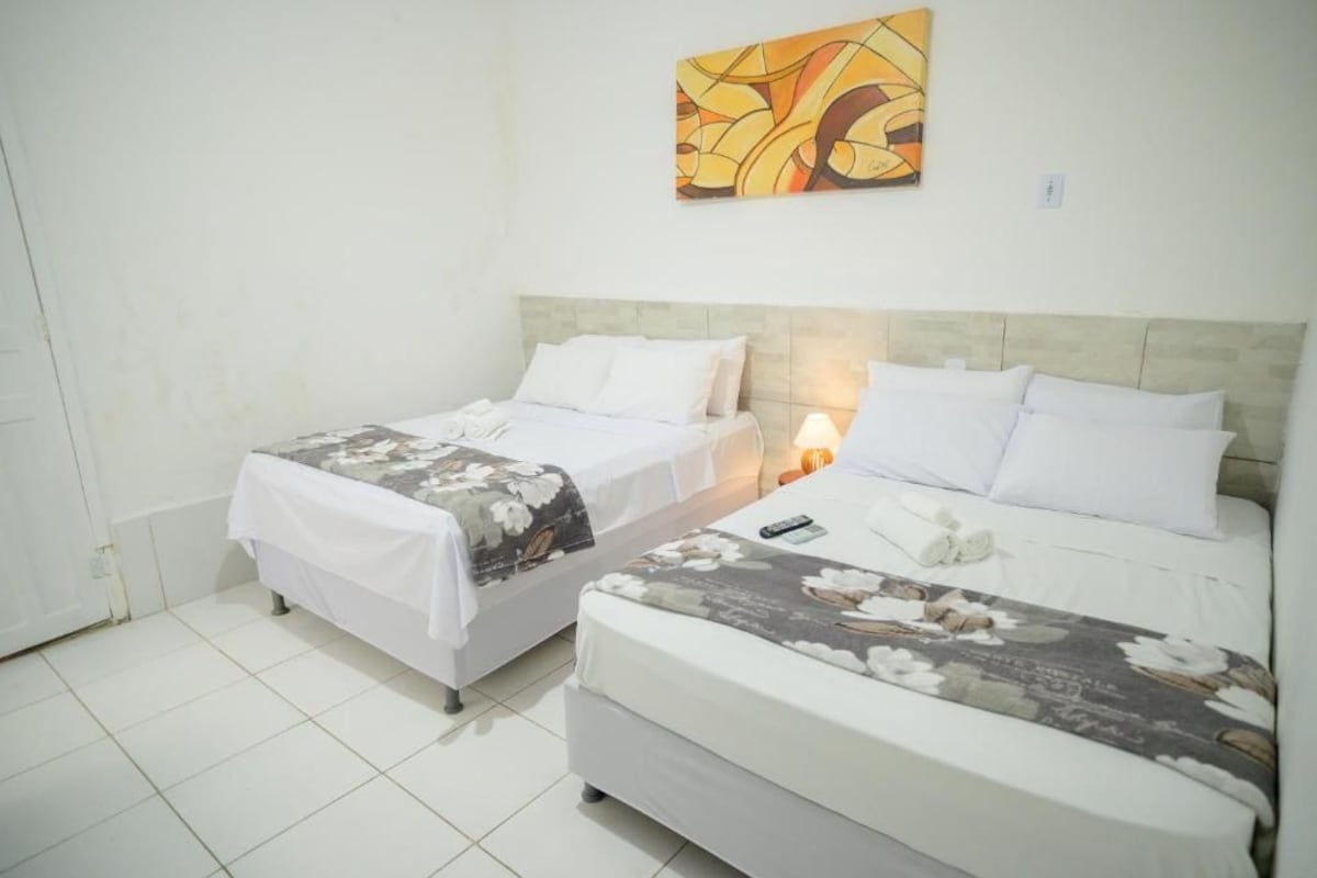 A hotel room with two beds, a nightstand, and a painting on the wall.