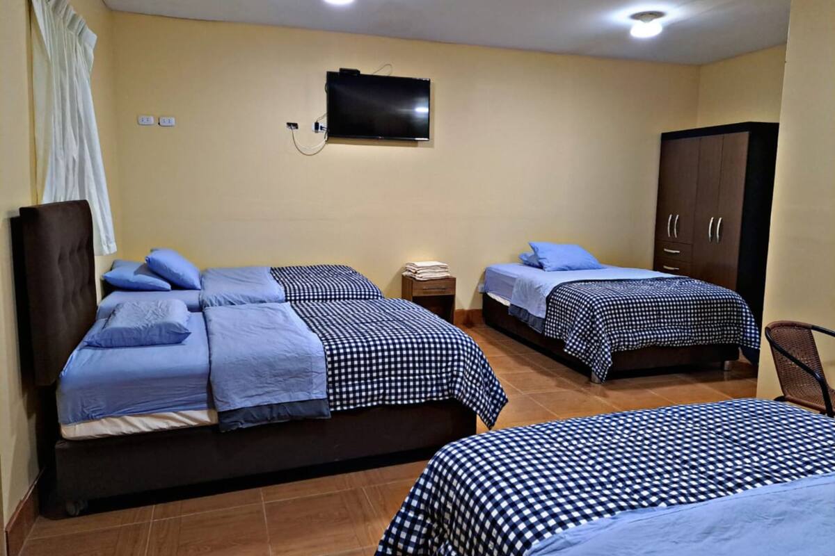 A hotel room with two beds, a television, a wardrobe, and a small table.