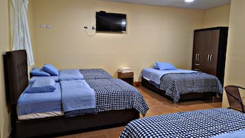 A hotel room with two beds, a television, a wardrobe, and a small table.