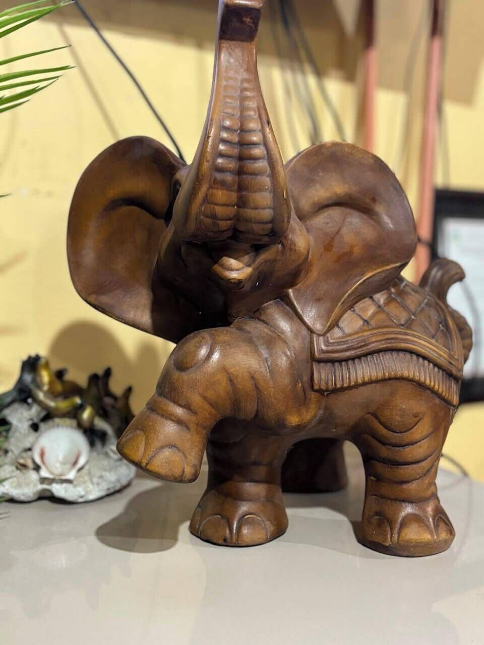 Una figurita de madera de elefante con trompa y silla de montar con textura.