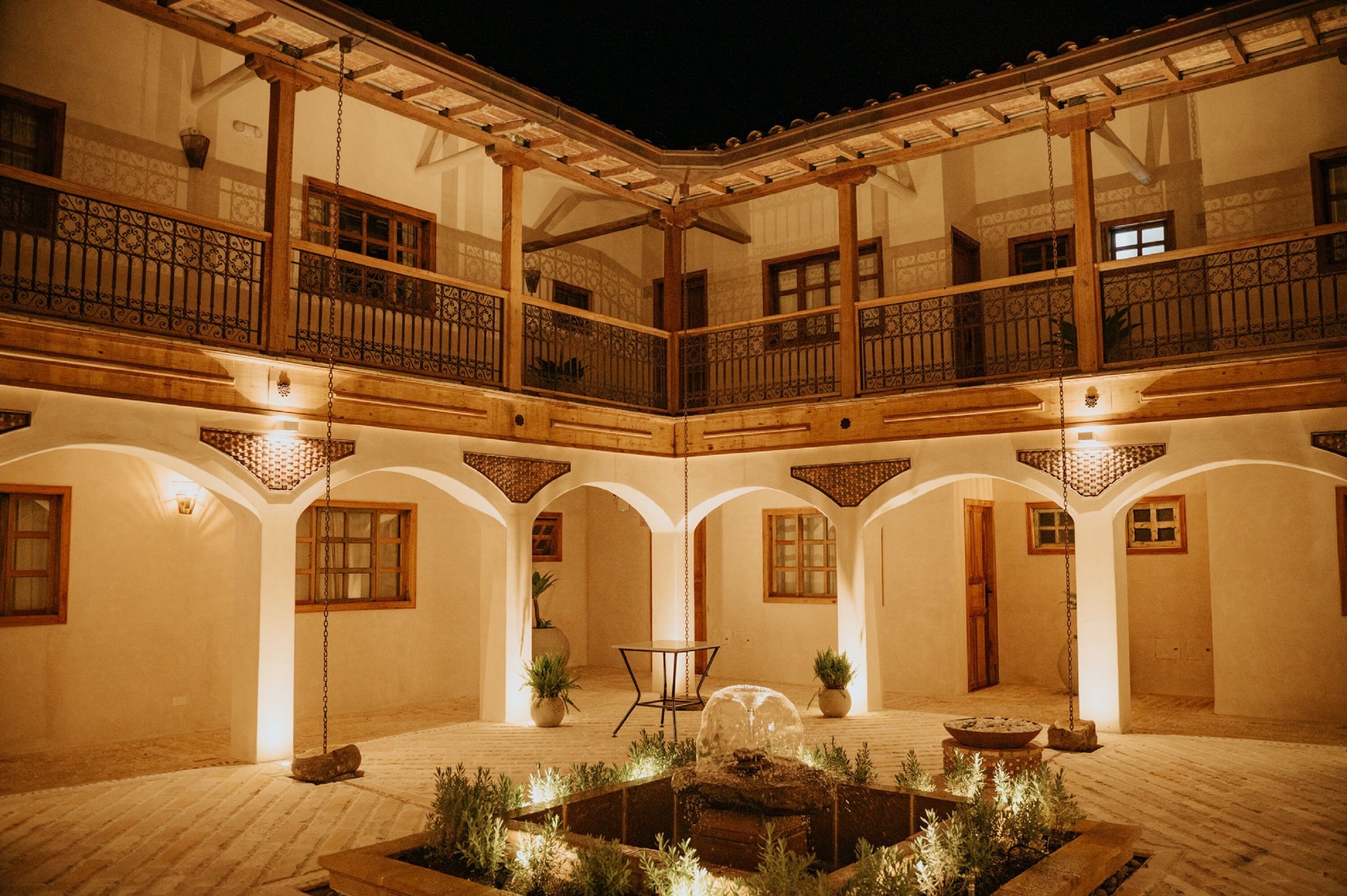 A courtyard with a fountain, potted plants, and a table.