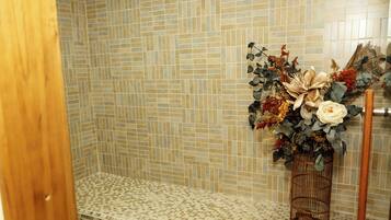 A bathroom with mosaic tile walls, a bench, and a floral arrangement in a wire basket.