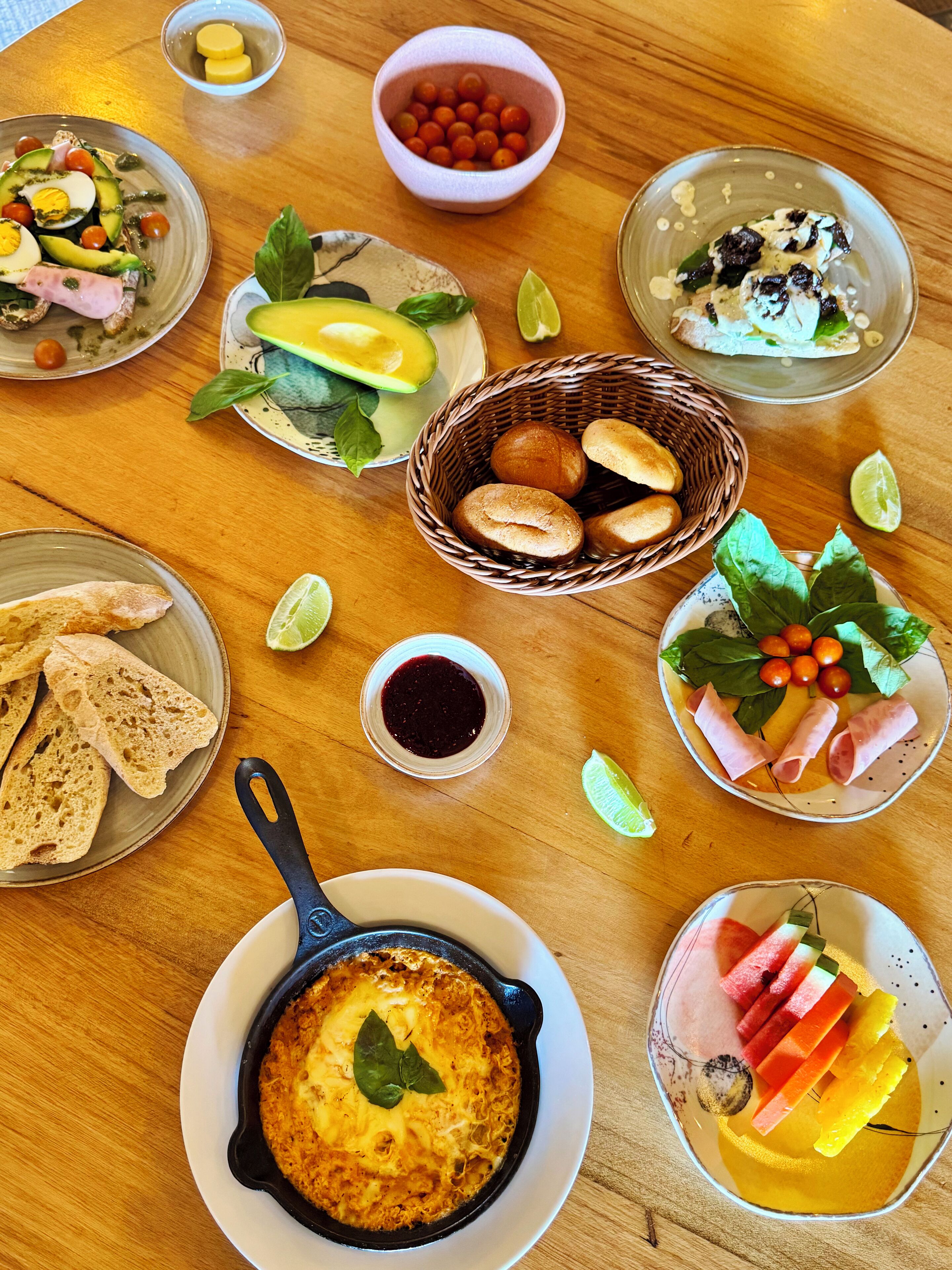 Une table en bois sur laquelle sont disposés divers aliments, notamment du pain, du fromage et des fruits.