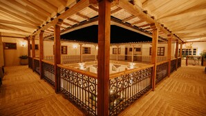 Un espacio interior cubierto con vigas de madera y suelo de vidrio, que incluye barandilla y varias ventanas.