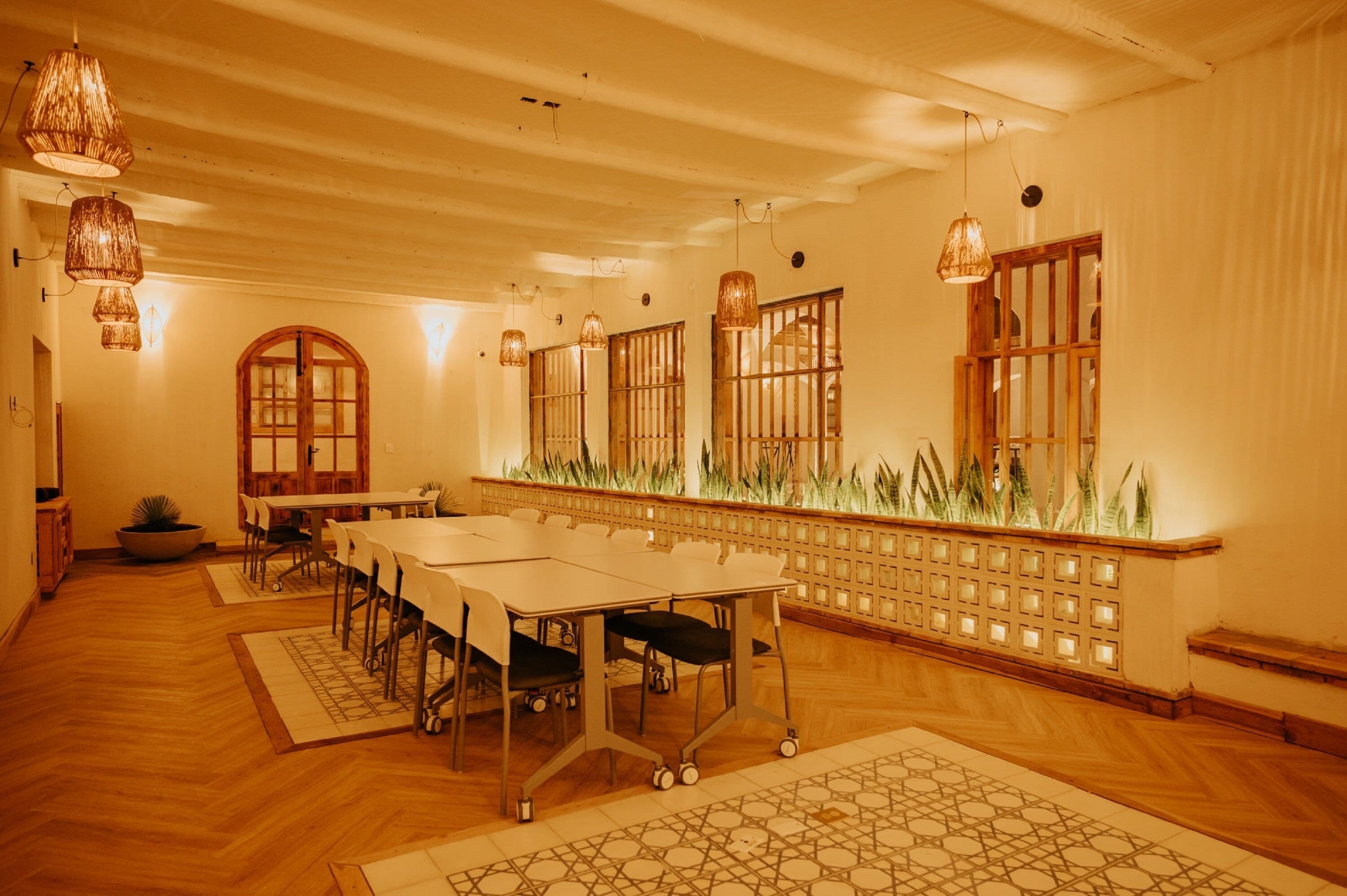 Une salle de conférence avec une longue table, des chaises et des lampes suspendues.