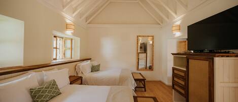 A hotel room with two beds, a TV, wooden furniture, and a mirror.