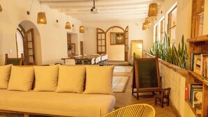 Una sala acogedora con sofá, sillones, una estantería y una zona de comedor al fondo.