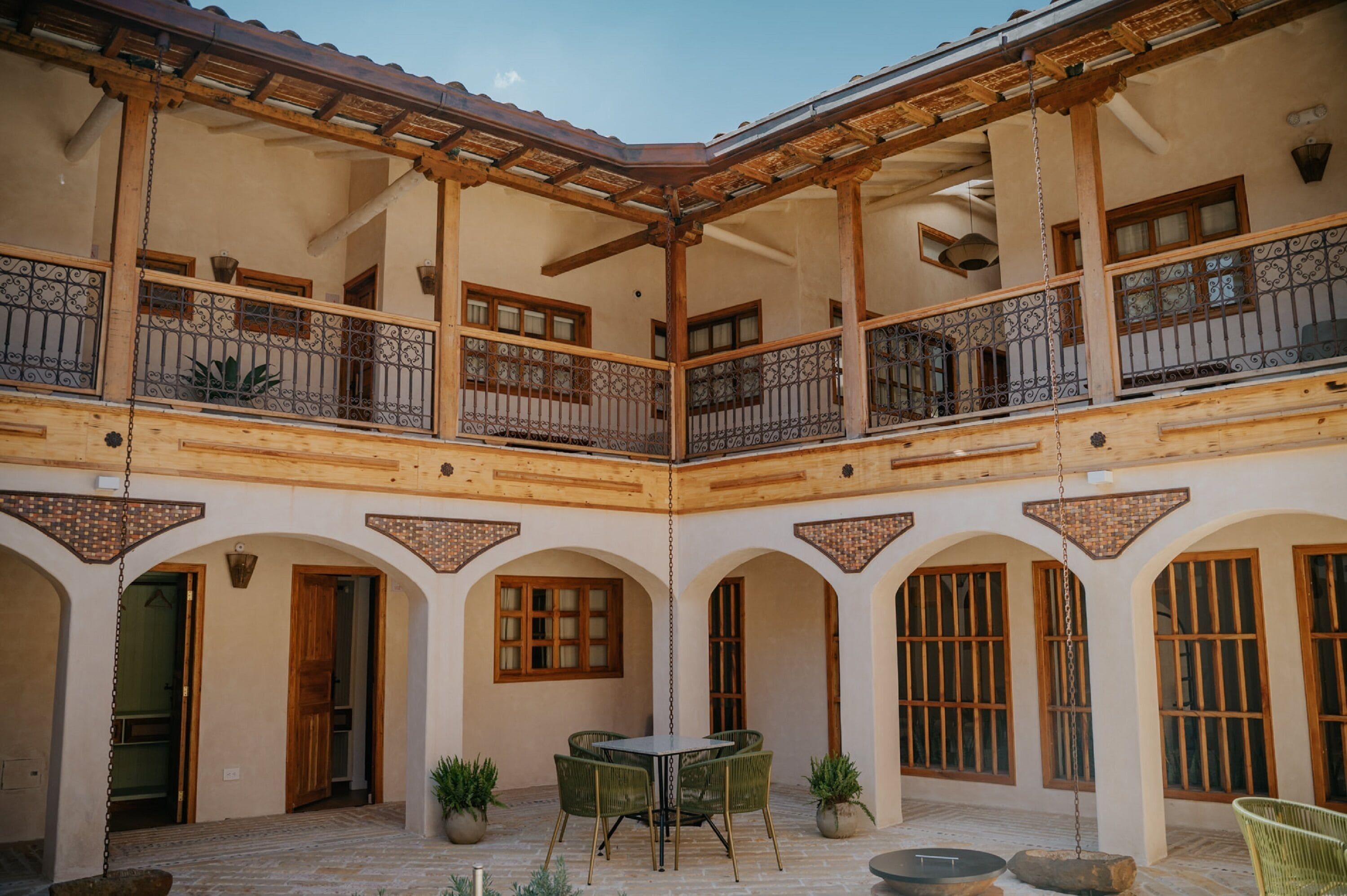 Un patio con una pérgola de madera, una mesa con sillas y plantas en macetas.
