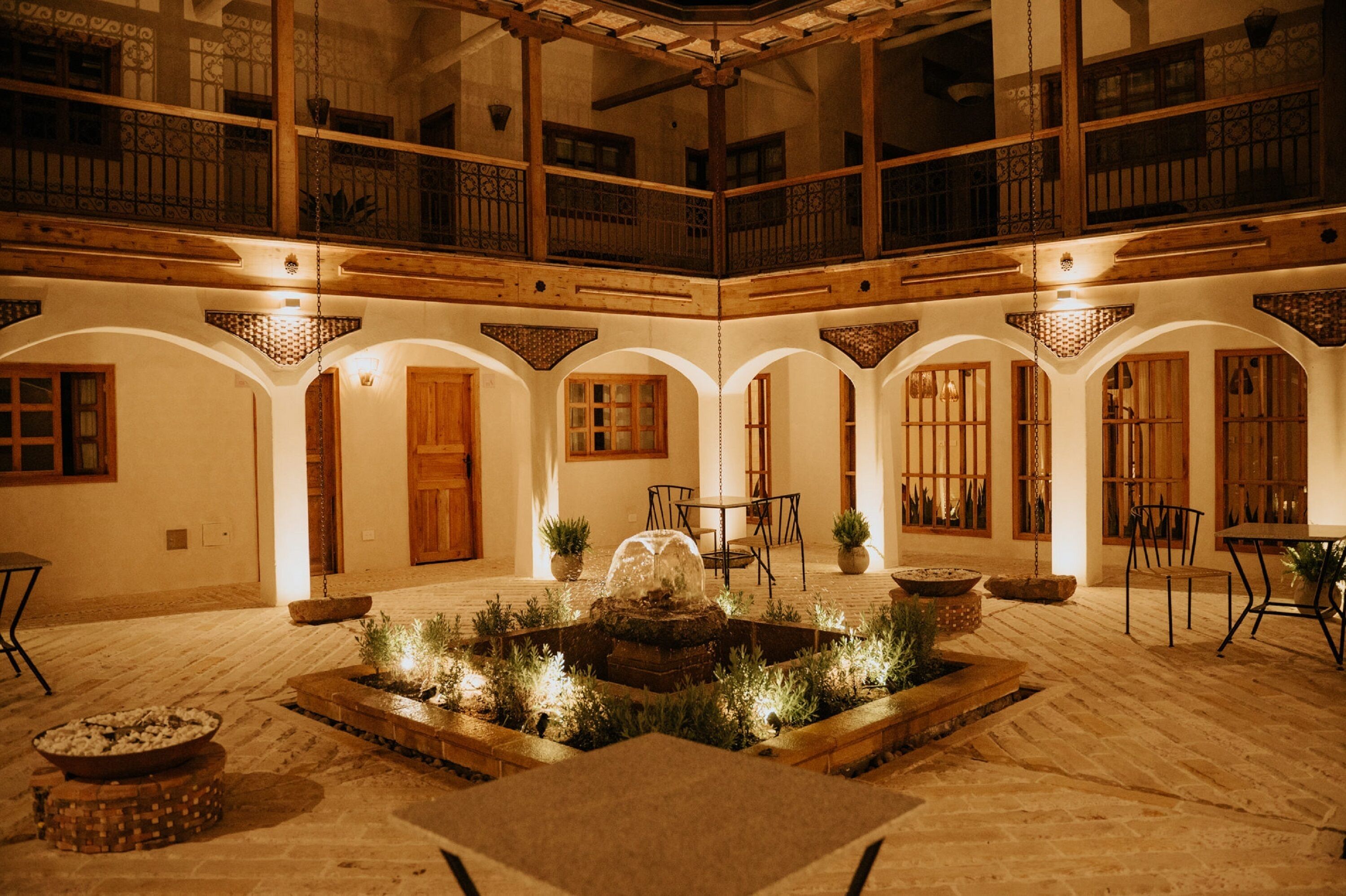 Un cortile con una fontana, mobili in legno e un balcone.