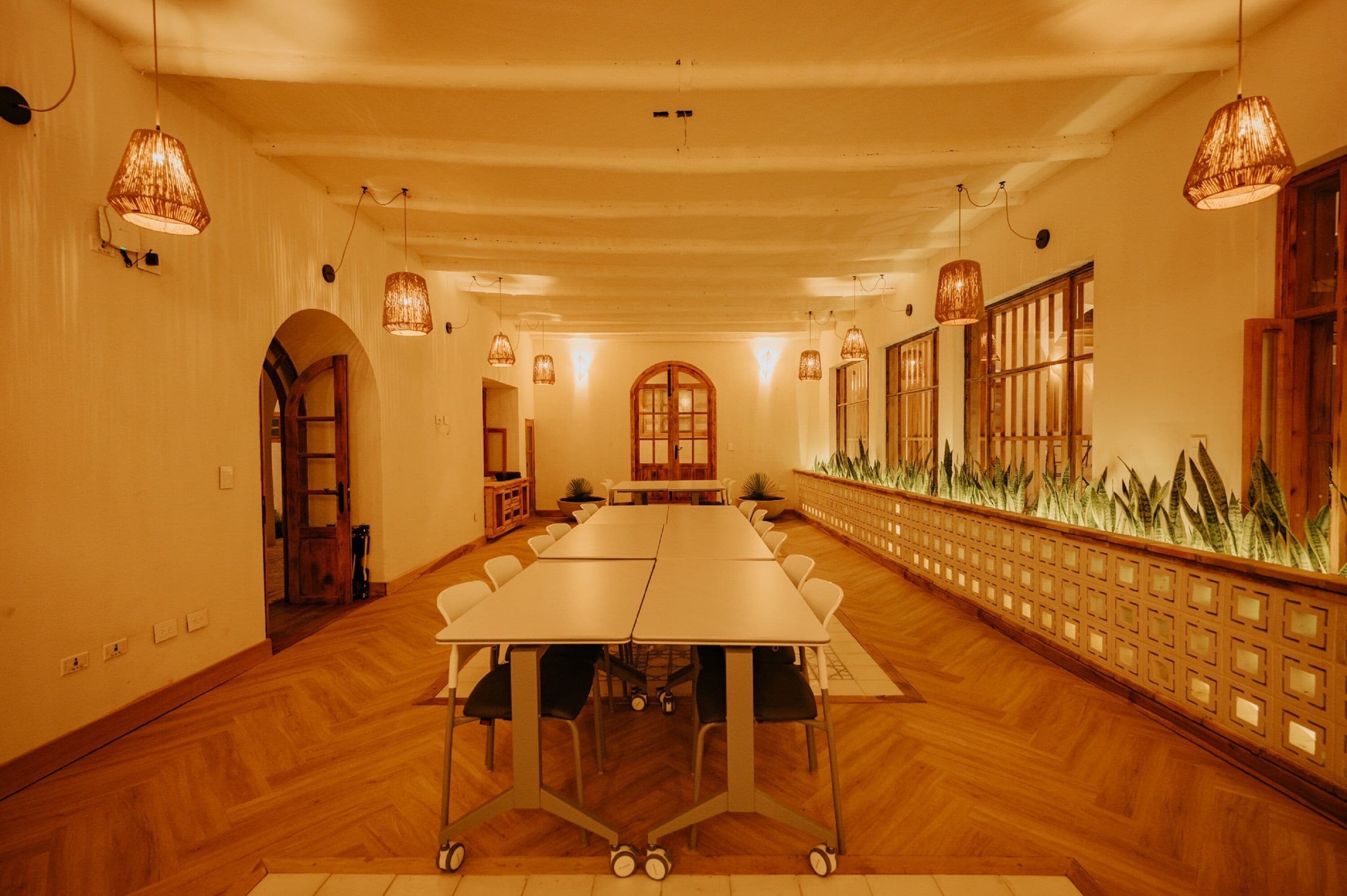Ein Konferenzraum mit einem langen Tisch, Holzböden und hängenden Lampen.