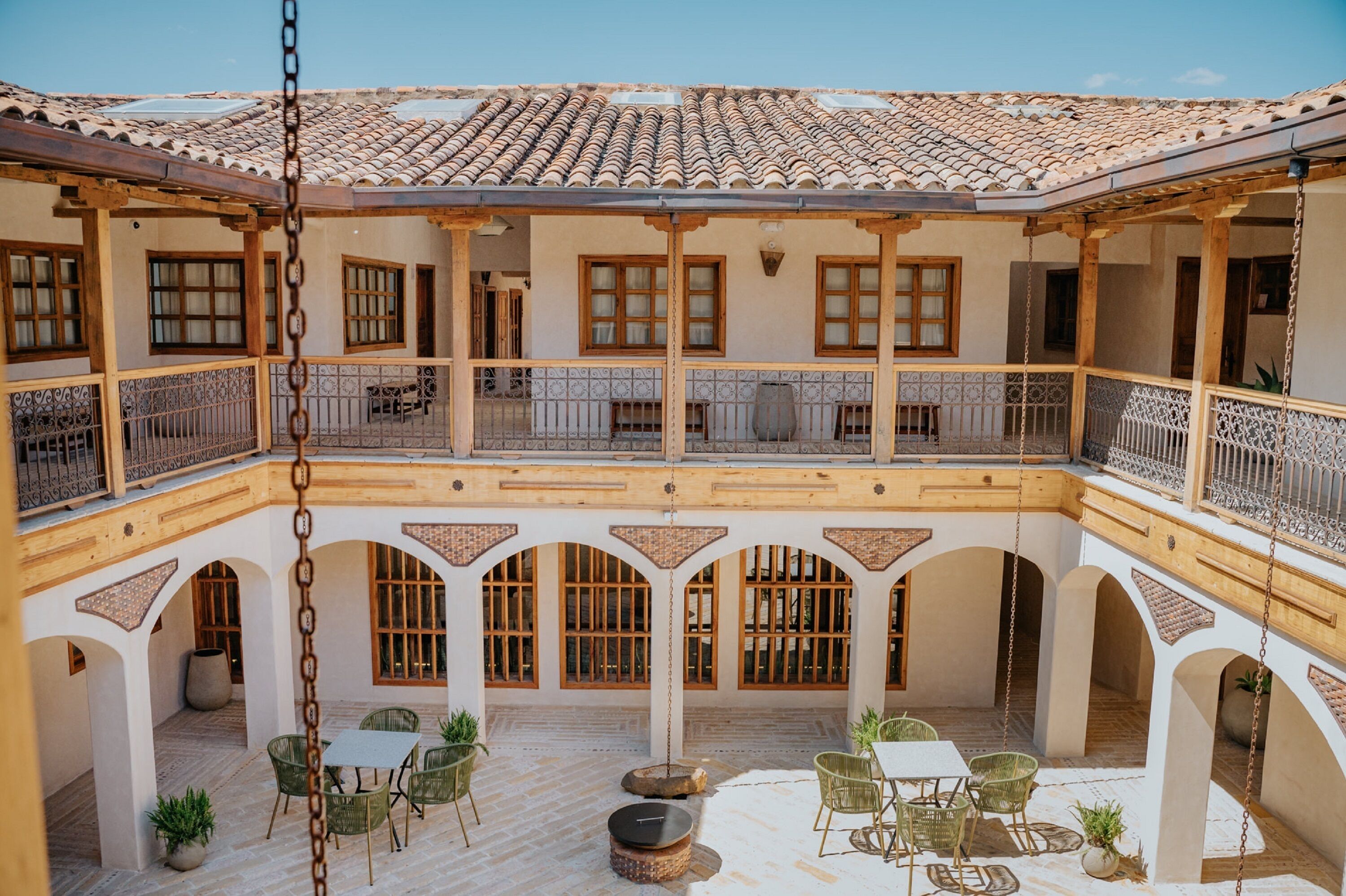 A courtyard with a tiled roof, wooden balconies, and outdoor seating areas.