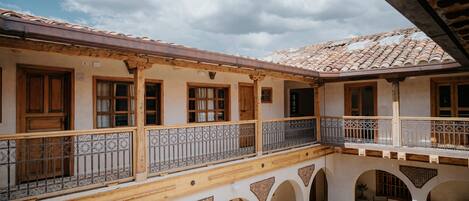 Un patio con techo de tejas, balcones de madera y arcos.