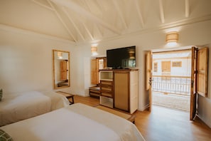 A bedroom with two beds, a TV, a wardrobe, and a balcony.