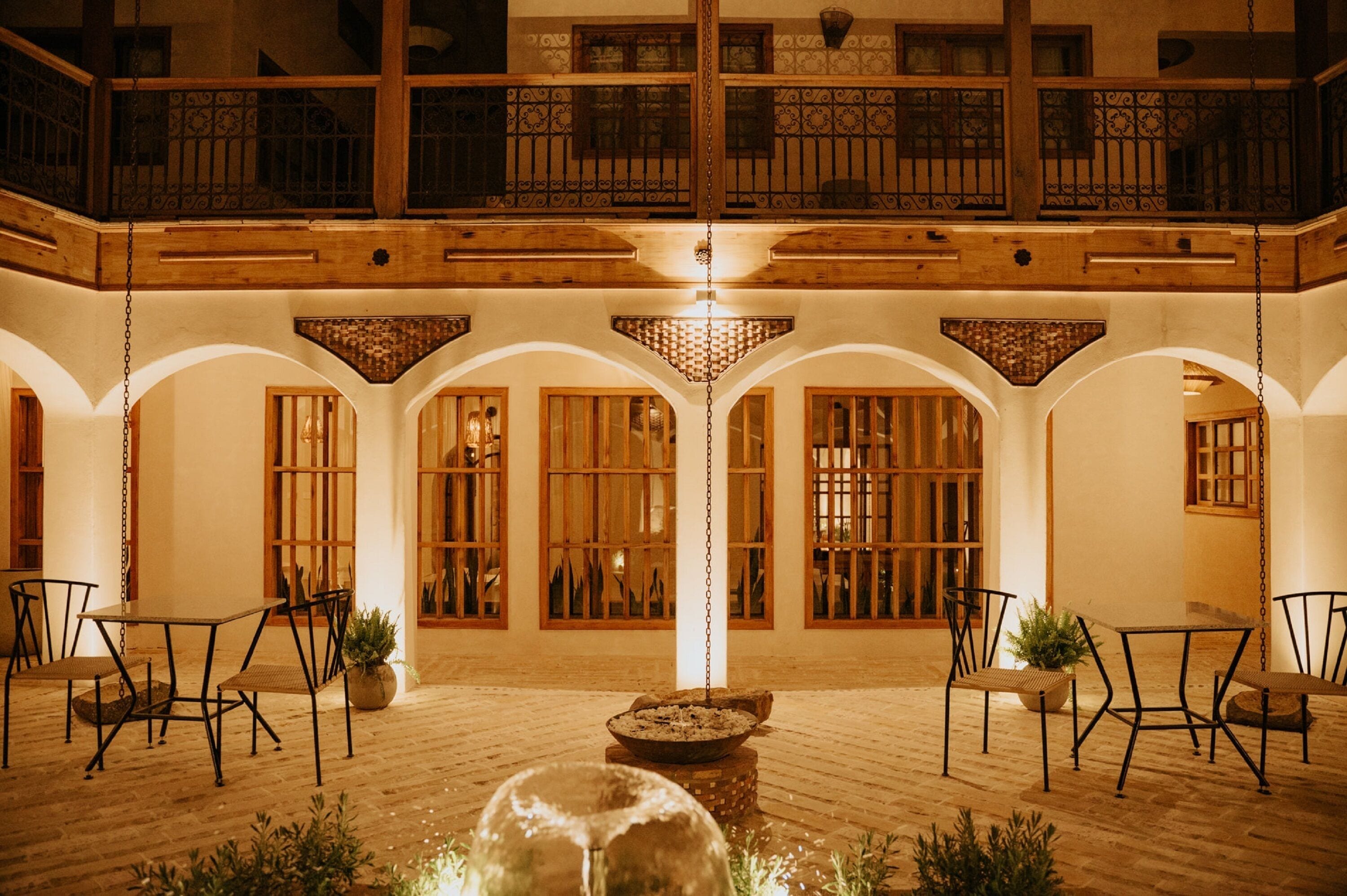 A spacious courtyard with wooden flooring, a central fountain, and seating areas.