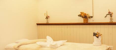 A wooden massage table with towels, a wooden bench, and a ceiling light fixture.