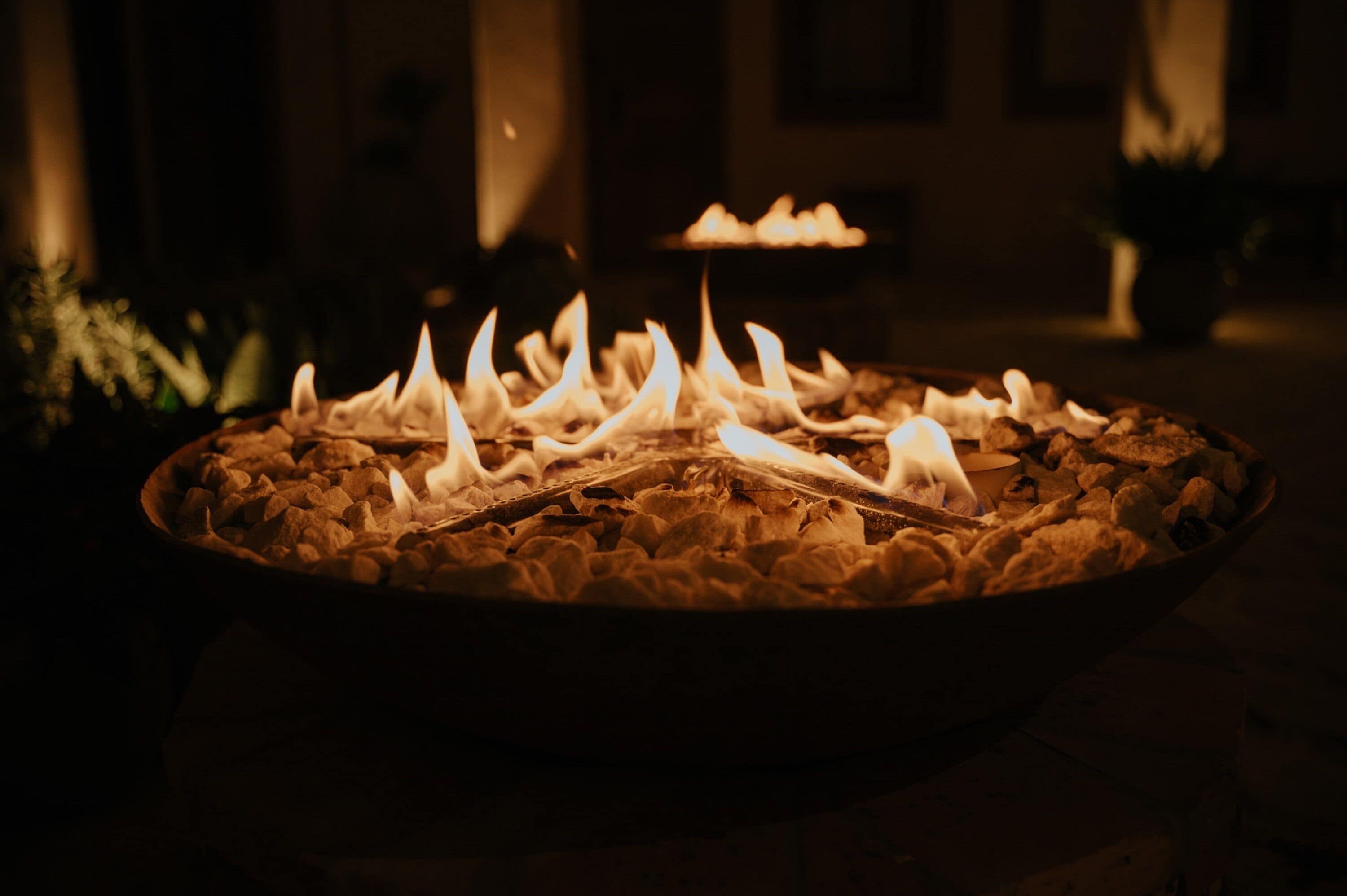 Un hoyo para fuego circular con leña ardiendo, rodeado de rocas.