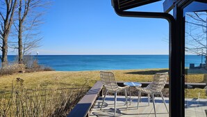 A patio with two wicker chairs and a table, overlooking a clear blue sea.