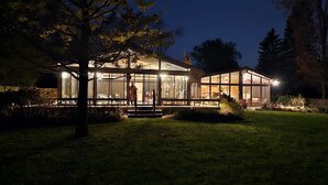 A modern house with large glass windows, a covered porch, and a well-maintained lawn.