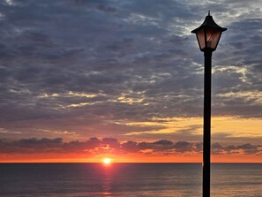 A sunset over the ocean with a street lamp in the foreground.