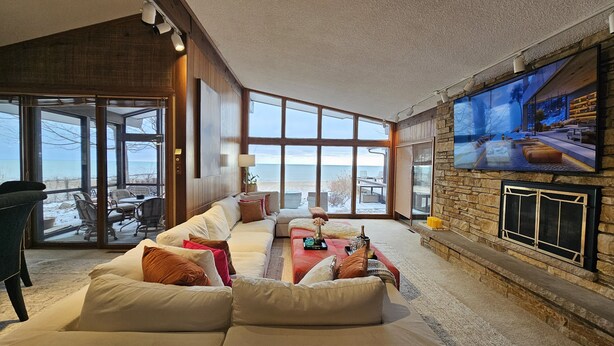 A spacious living room with a large window, a fireplace, and a television.