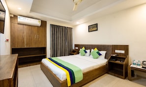 Habitación de hotel con cama de madera, mesita de noche, armario y un cuadro en la pared.