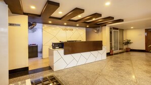 A reception desk with a modern design, a sign indicating a wash room, and a reception area with a glass door. - Swagatam Inn (Guwahati)