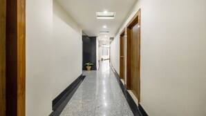 A hallway with a polished floor, a potted plant, and a door on the right. - Swagatam Inn (Guwahati)