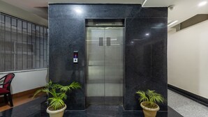 An elevator with a digital display, flanked by two potted plants. - Swagatam Inn (Guwahati)