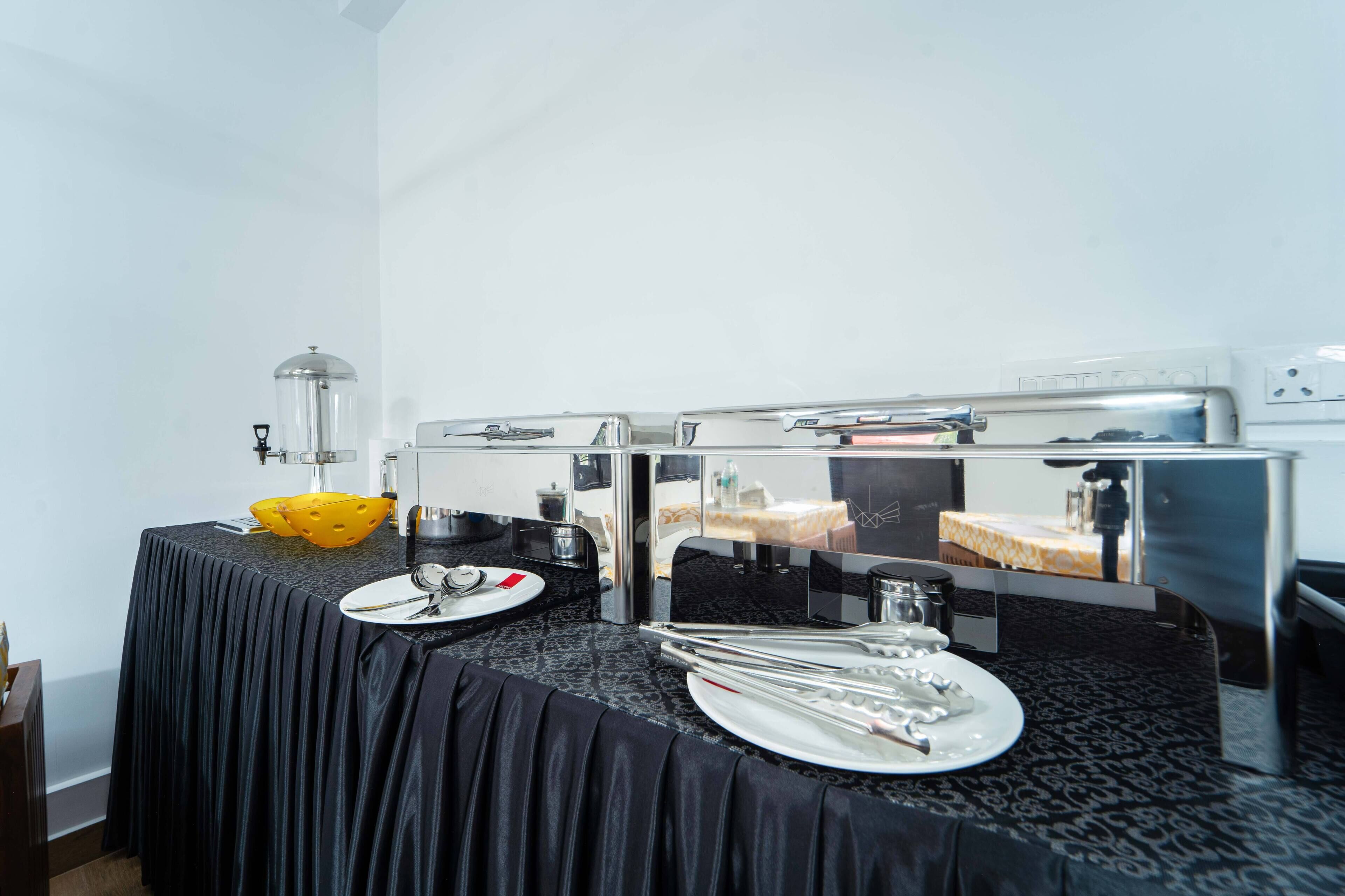 Un buffet avec une nappe noire, des ustensiles de service et un saladier jaune.