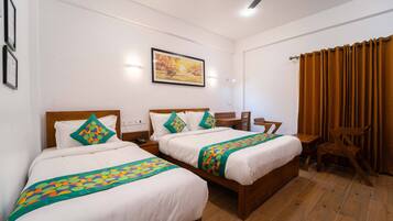 Quarto de hotel com duas camas, uma escrivaninha, uma cadeira e um quadro na parede.