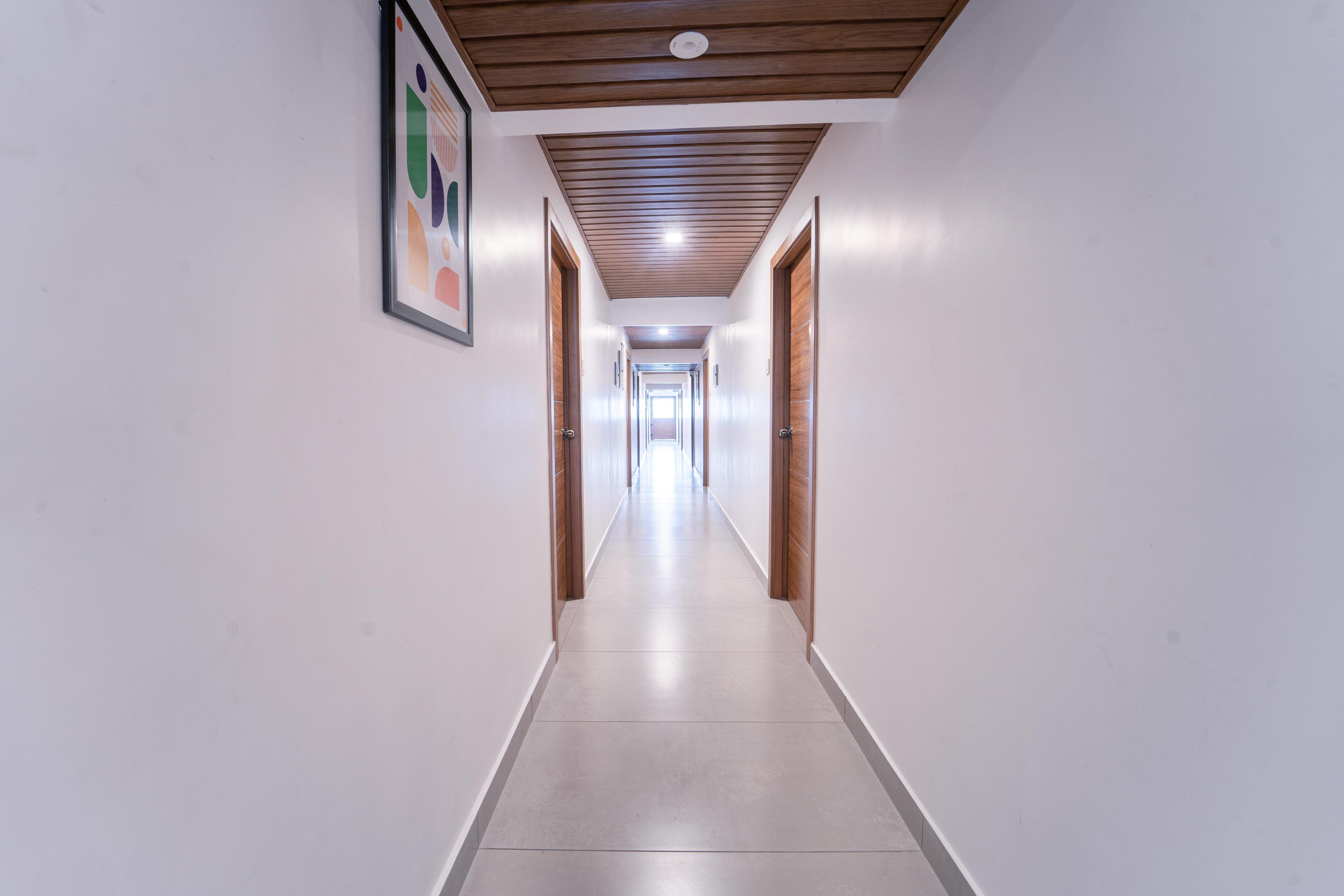 A long, narrow hallway with wooden doors on both sides and a tiled floor.