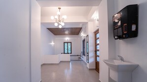 A modern hallway with a white sink, wooden ceiling, and a wall-mounted dispenser. - Treebo West Fort Divine – Near Padmanabhaswamy Temple (Thiruvananthapuram)
