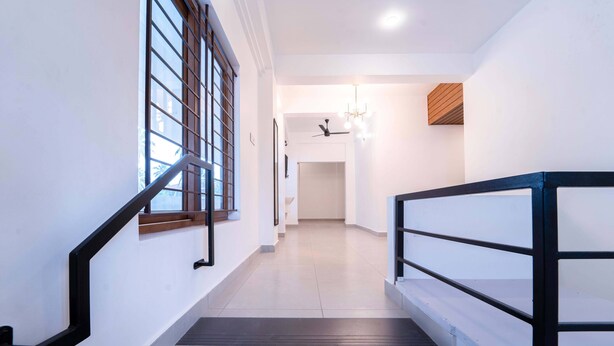A modern interior with a staircase, a ceiling fan, and a light fixture. - Treebo West Fort Divine – Near Padmanabhaswamy Temple (Thiruvananthapuram)
