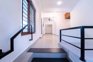 A modern interior with a staircase, a ceiling fan, and a light fixture. - Treebo West Fort Divine – Near Padmanabhaswamy Temple (Thiruvananthapuram)