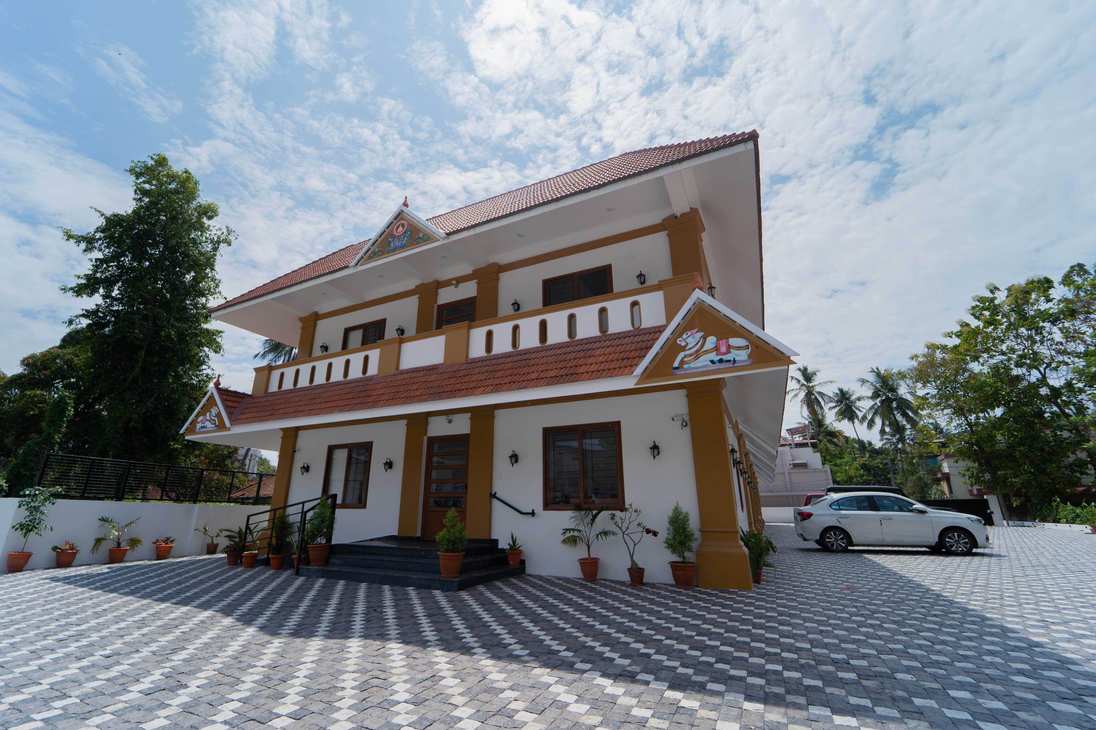 A two-story building with a tiled roof, a balcony, and a car parked in front.