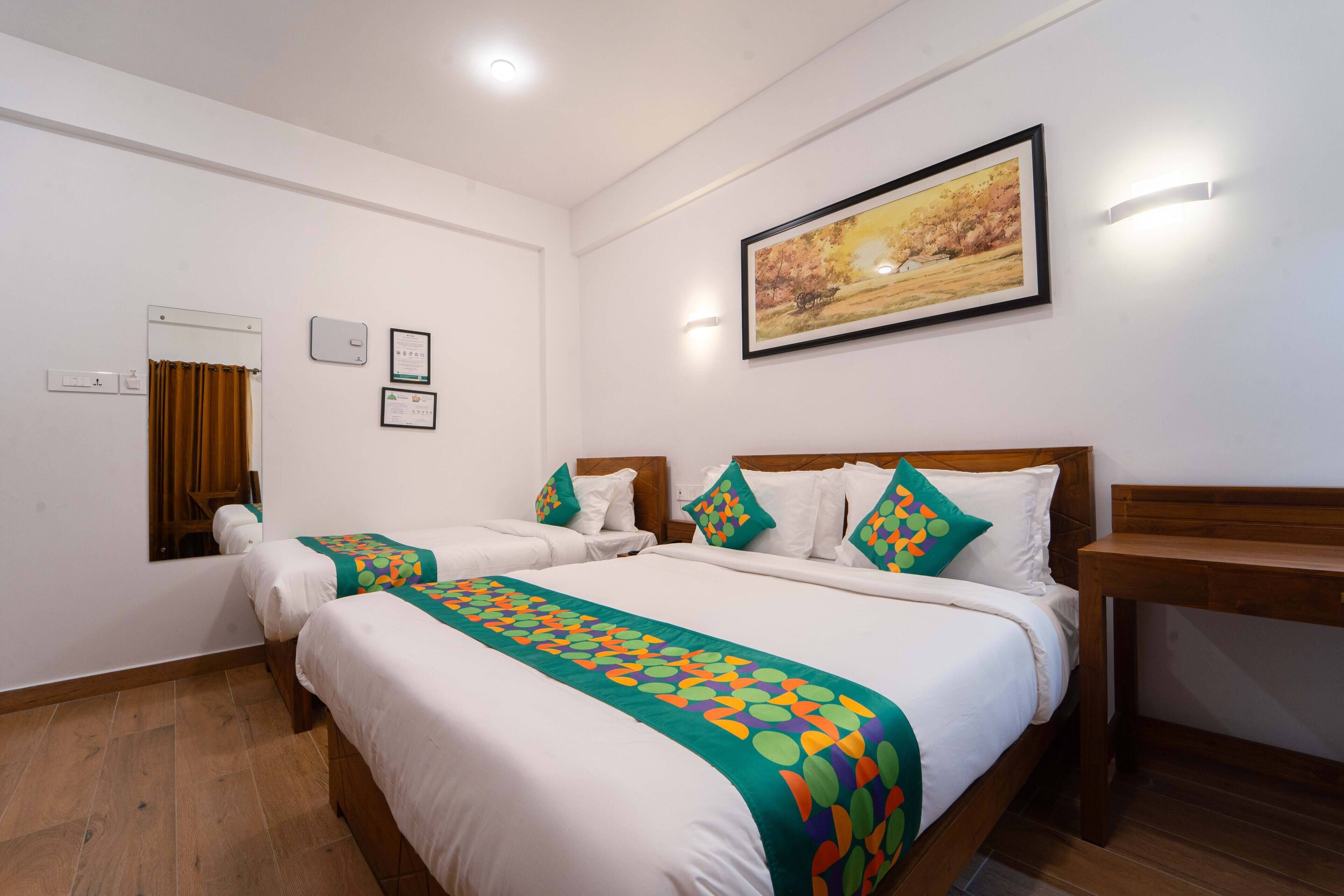 A hotel room with two beds, a wooden headboard, a painting on the wall, and a small table.