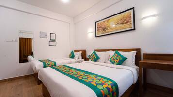 A hotel room with two beds, a wooden headboard, a painting on the wall, and a small table.