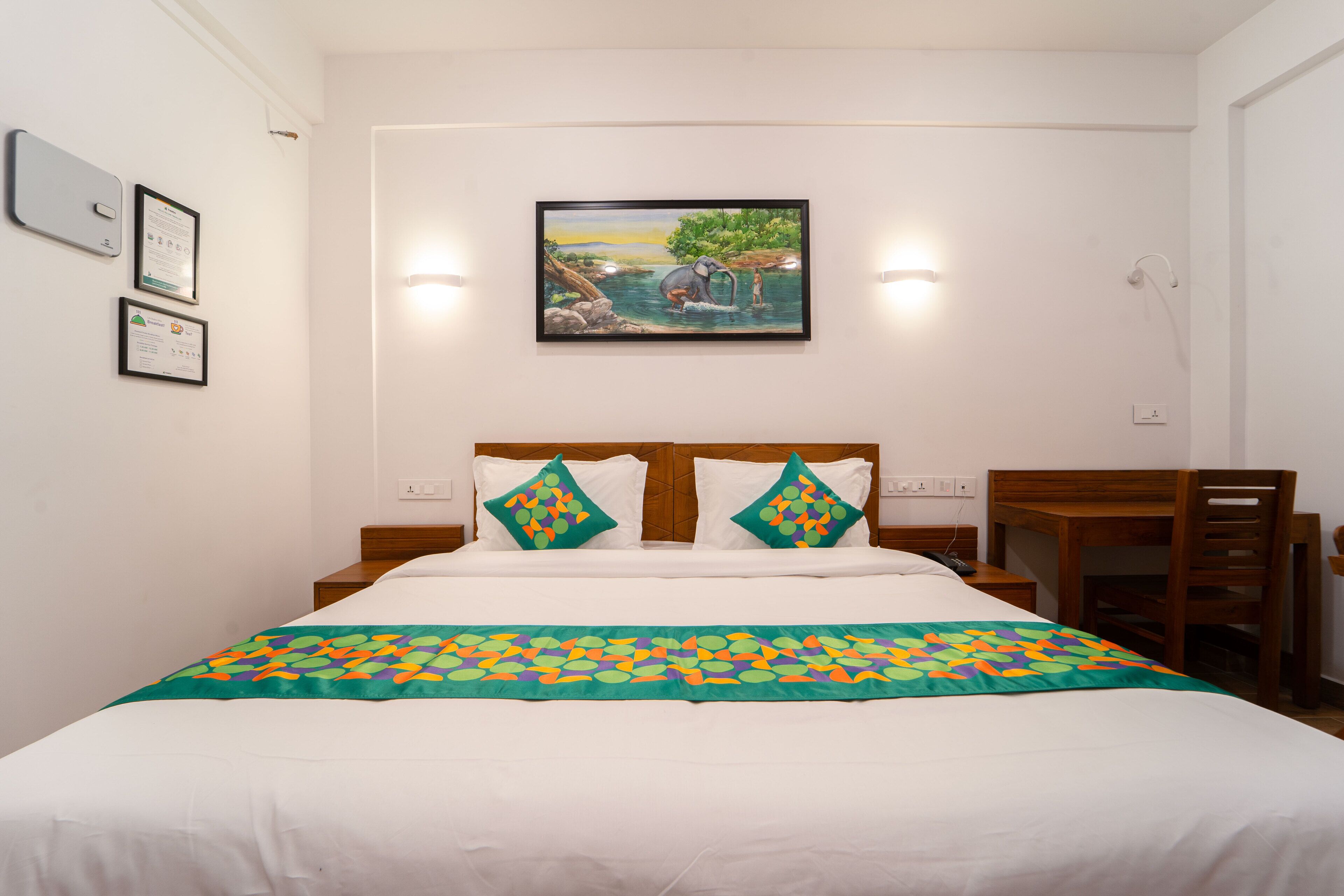 Una cama bien tendida con un edredón colorido, un cabecero de madera y dos almohadas con un estampado geométrico.