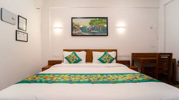 Una cama bien tendida con un edredón colorido, un cabecero de madera y dos almohadas con un estampado geométrico.