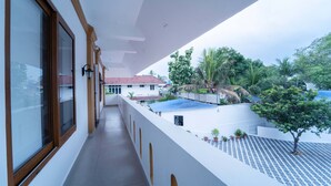 A balcony with a view of a garden and a building with a red roof. - Treebo West Fort Divine – Near Padmanabhaswamy Temple (Thiruvananthapuram)