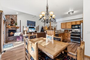 Amplia sala de estar con chimenea, mesa de comedor de madera y cocina con armarios de madera.
