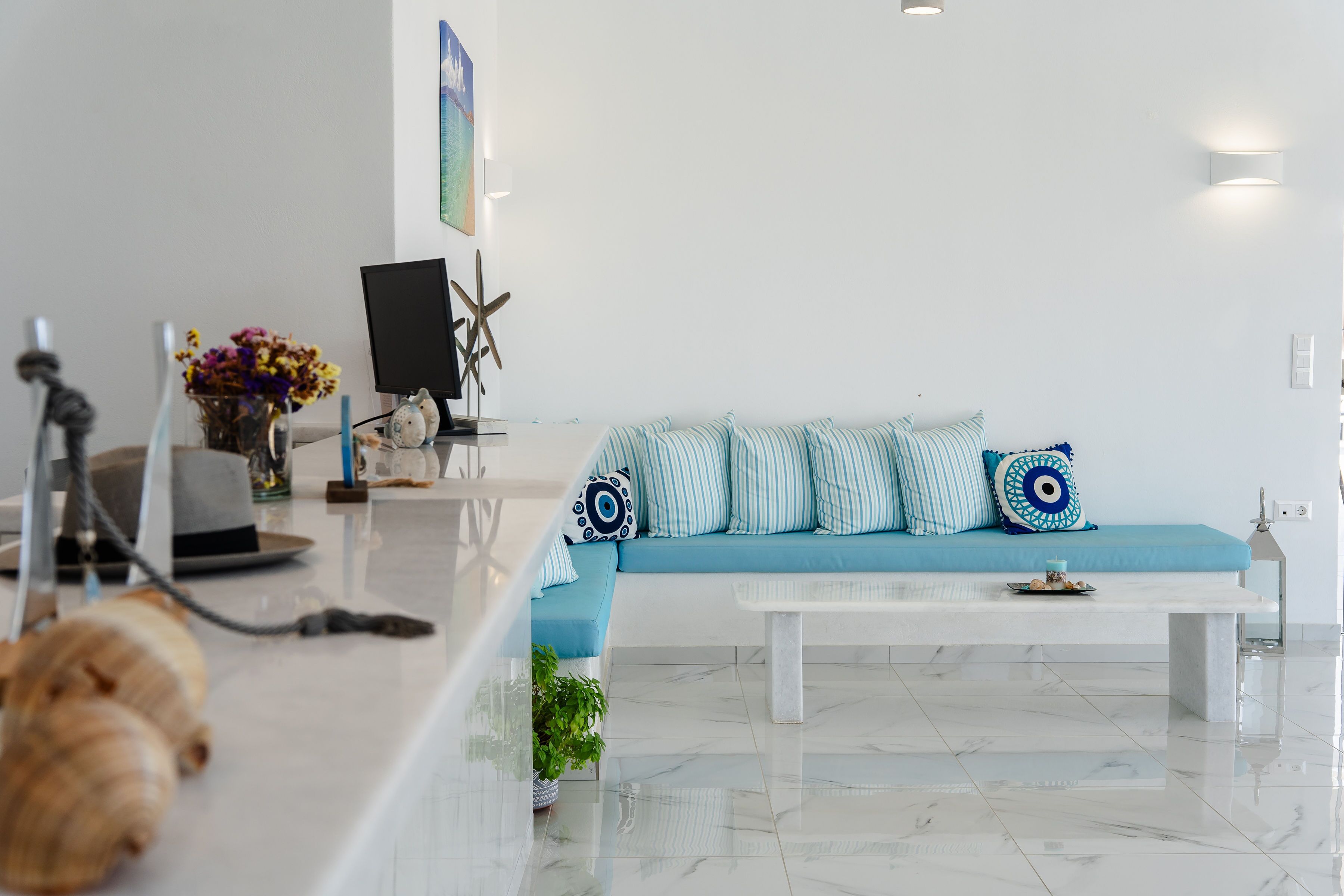 Una sala moderna con un sofá azul, almohadones a rayas, una mesita de centro blanca y una planta decorativa.