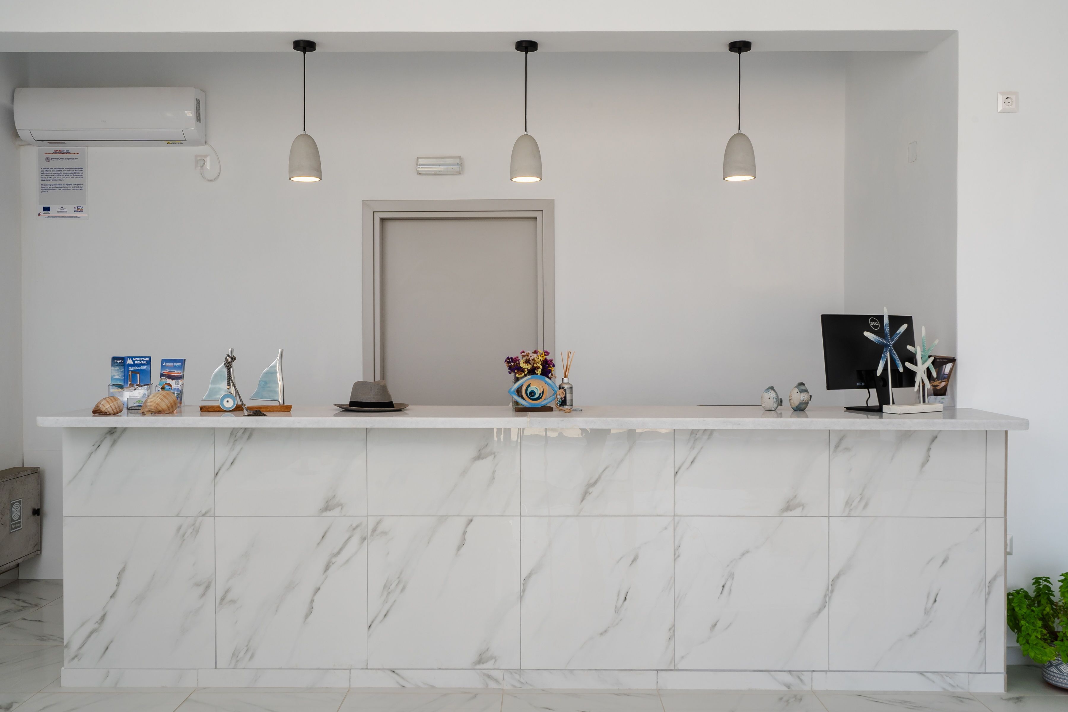 A reception desk with a marble top, pendant lights, a TV, and decorative items.