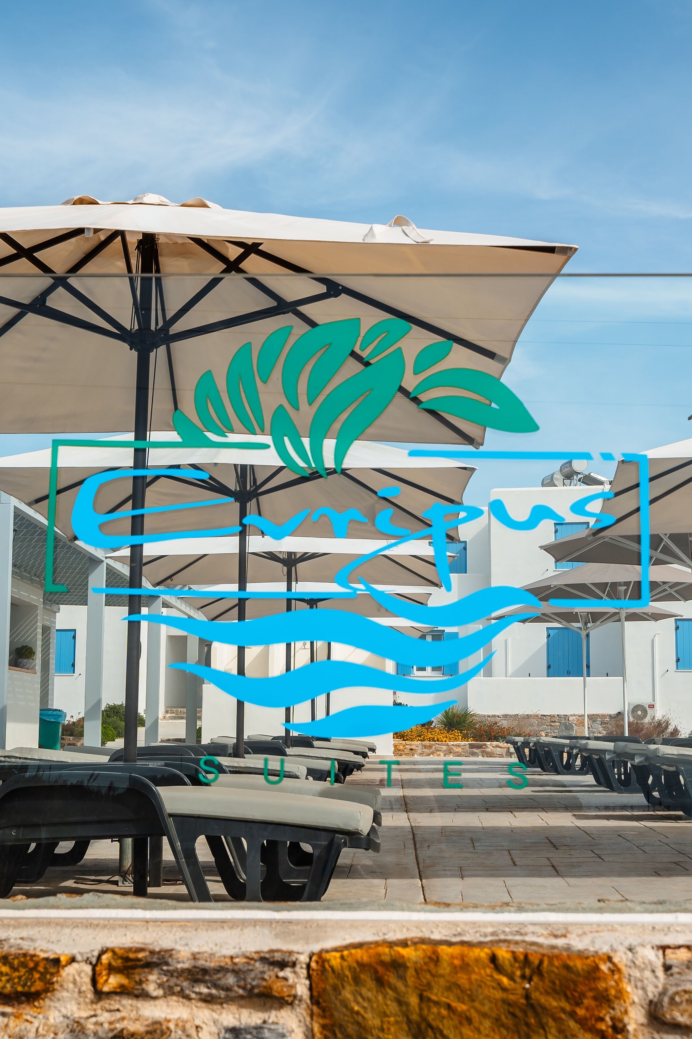 A beachside area with umbrellas, lounge chairs, and a clear sky.