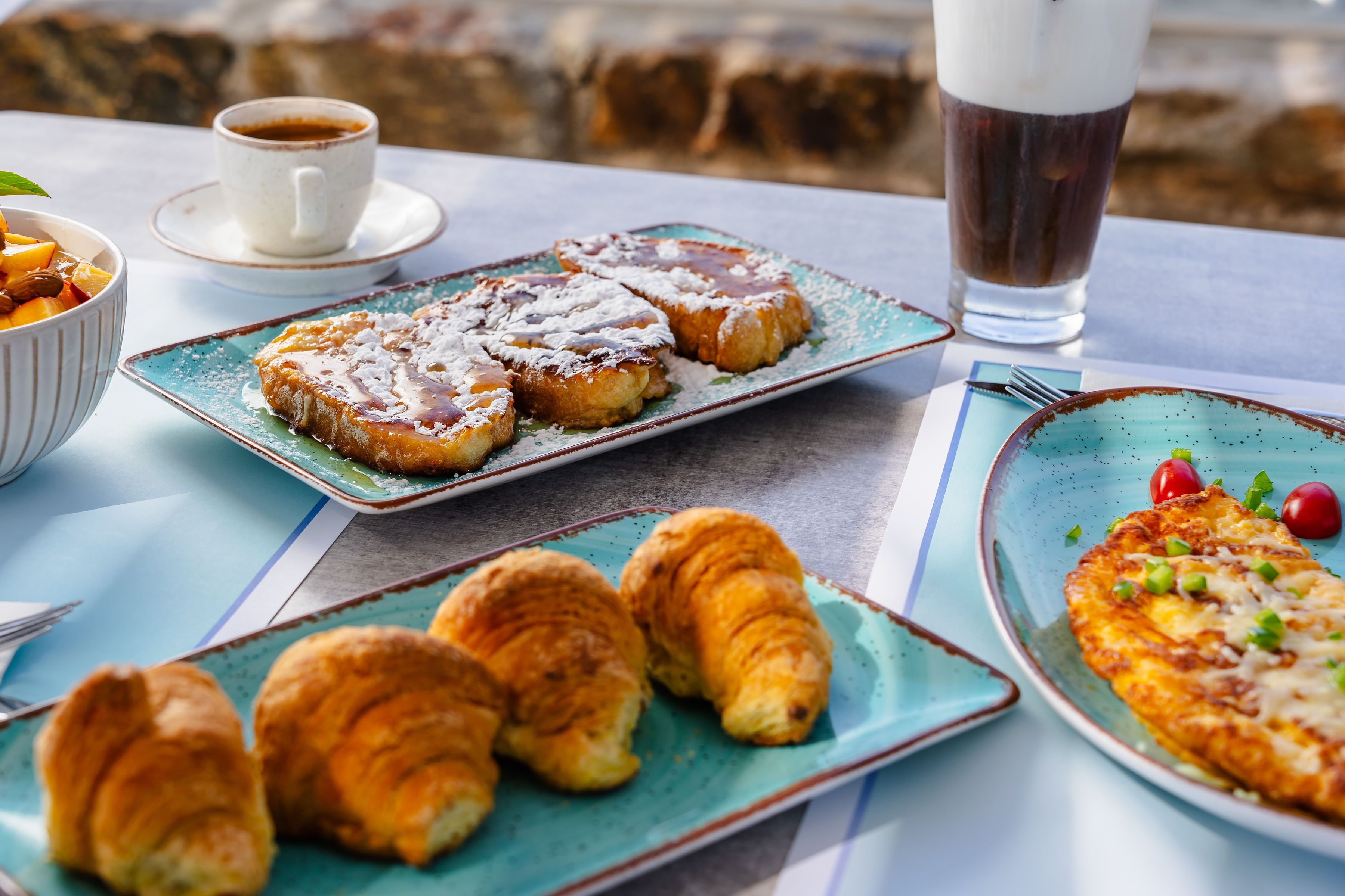 A table with breakfast items including croissants, toast, and a plate with a vegetable omelette.