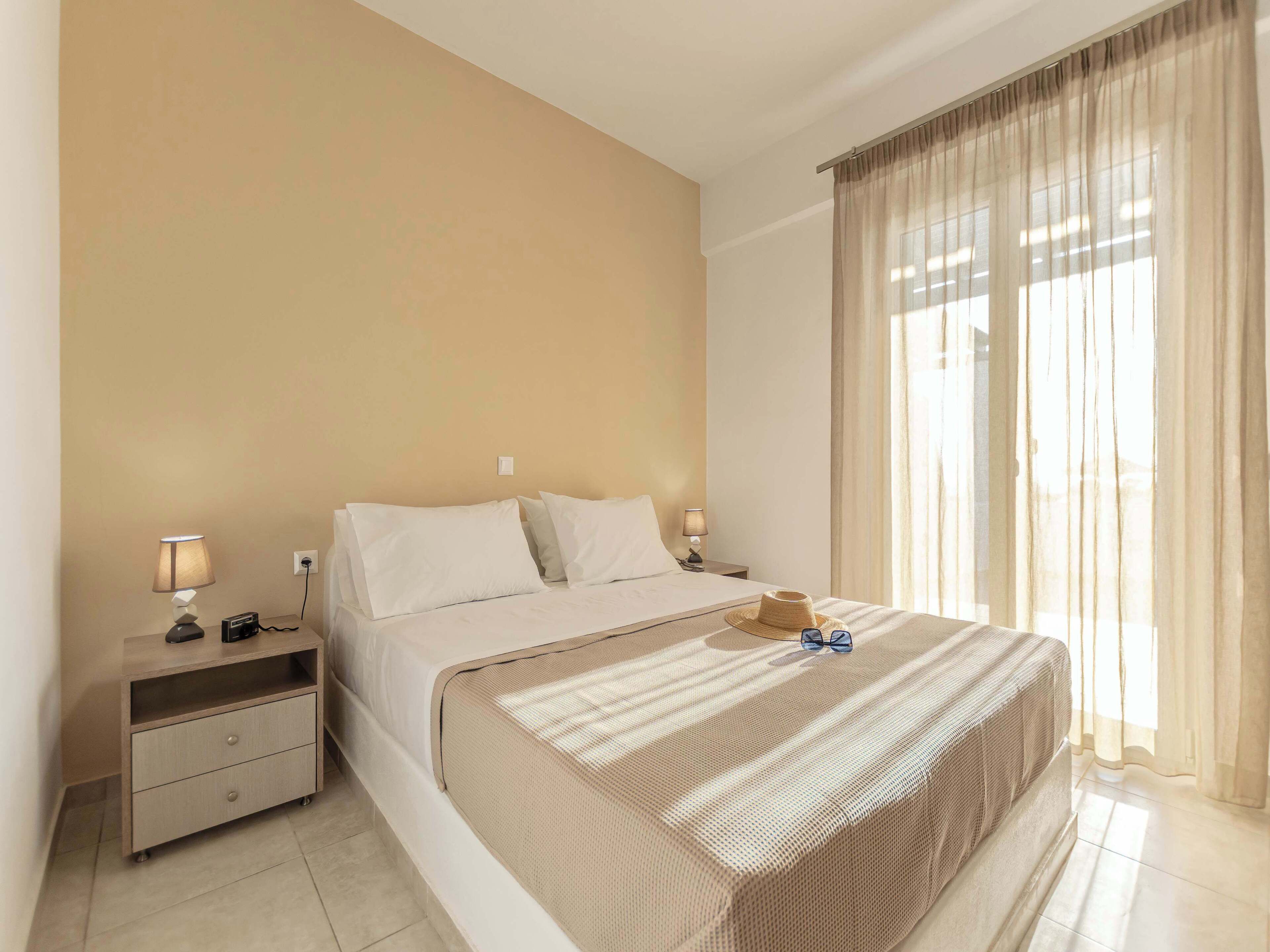 A hotel room with a bed, bedside tables, a lamp, and a window with curtains.