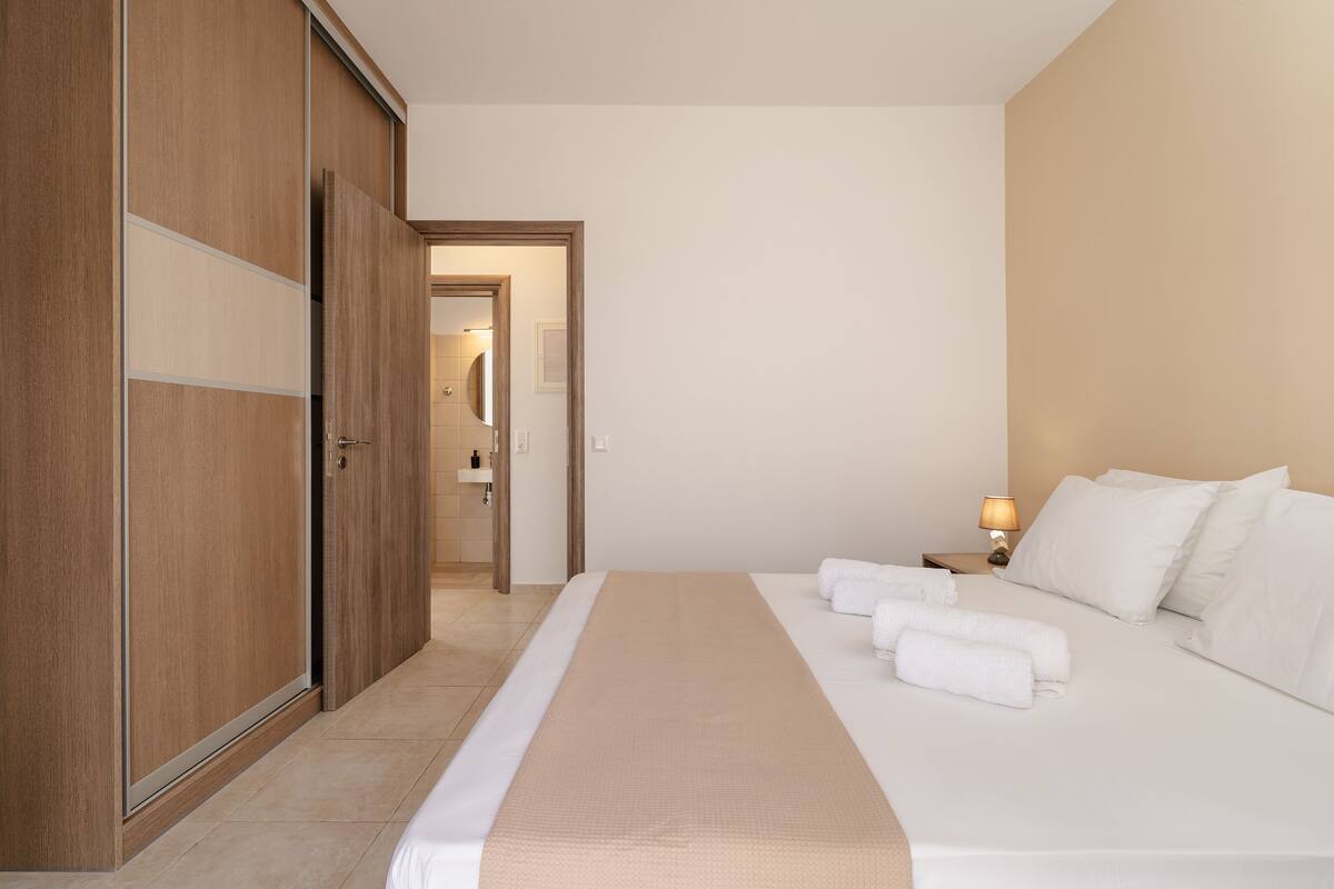 A hotel room with a large bed, a wardrobe, and a bathroom visible through an open door.